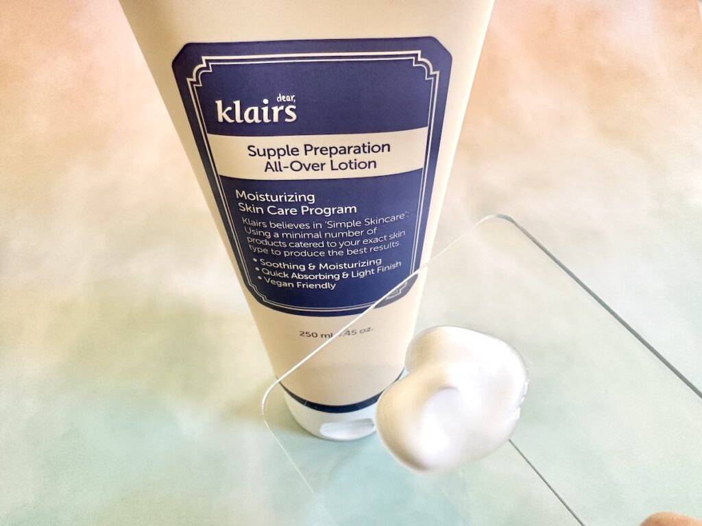 Klairs Supple Preparation All-Over Lotion bottle behind lotion sample on clear spatula.
